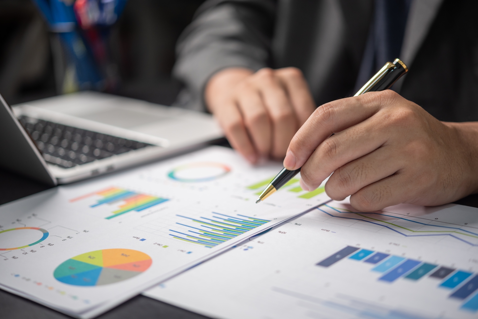 An analyst reviewing charts and data beside a laptop.