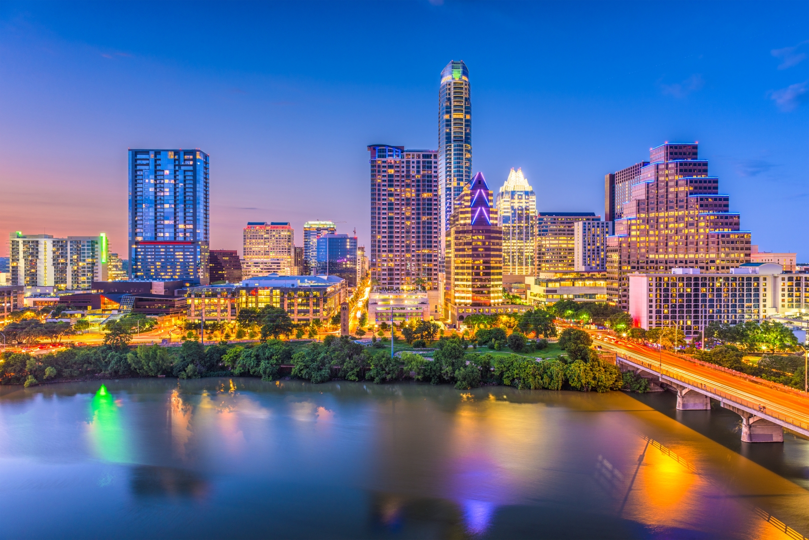 The Austin skyline and a bridge over Lady Bird Lake at dusk.