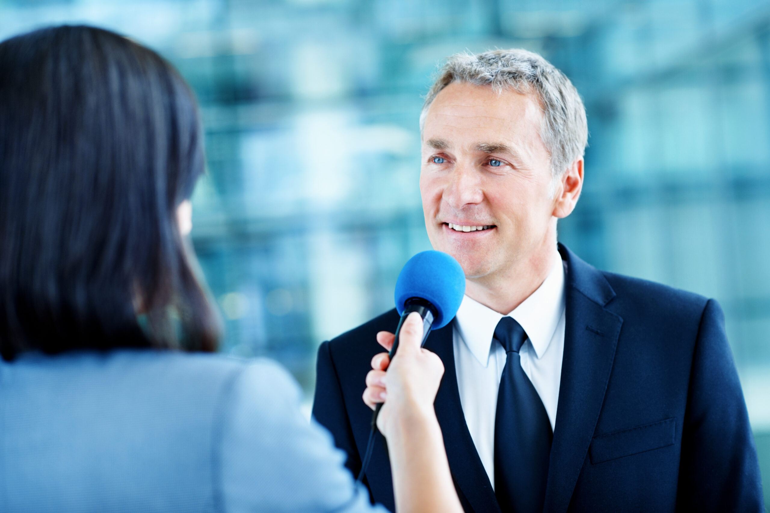 Executive answering questions from a reporter holding a microphone